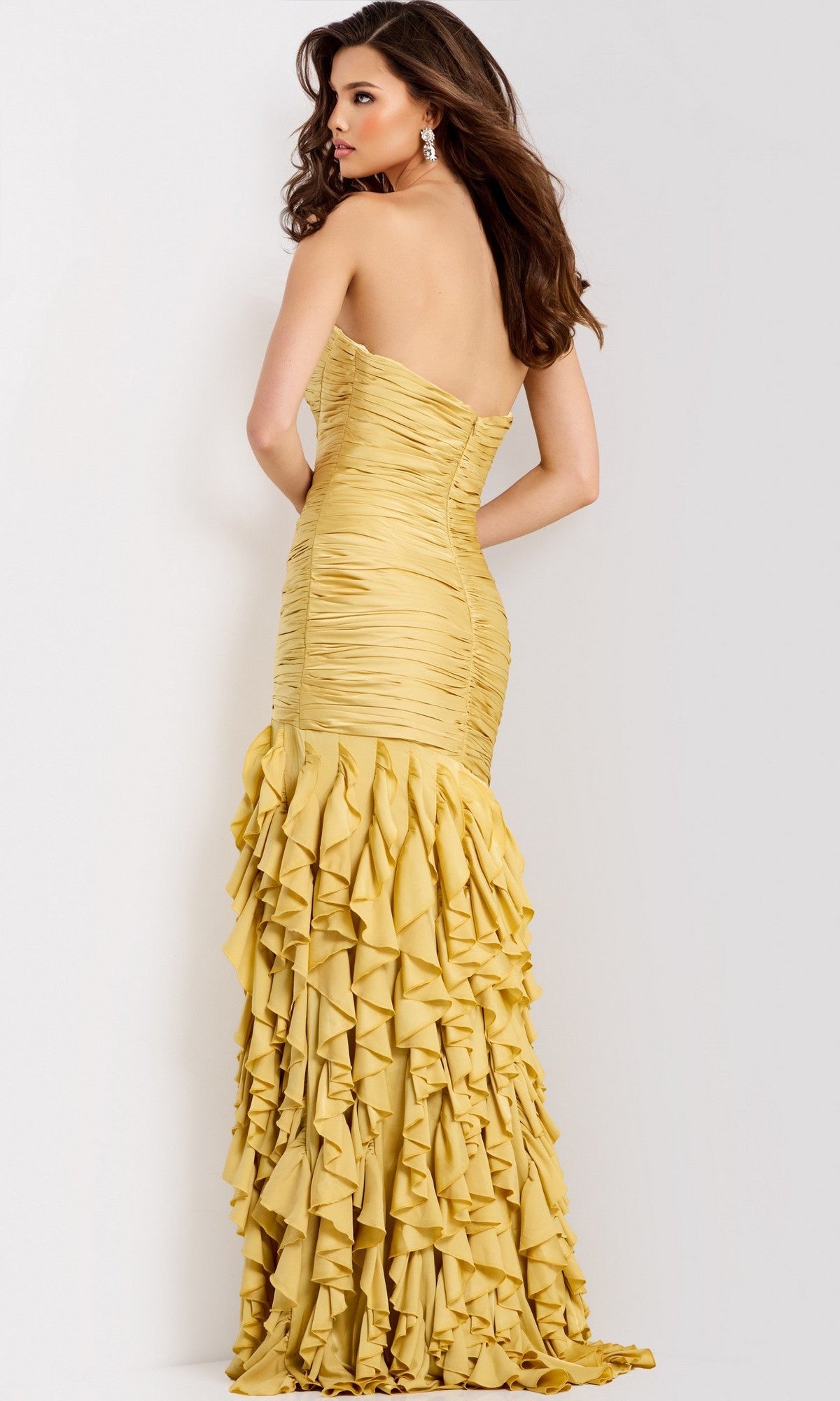 A woman in the Jovani 47553 Ruffle-Skirt Strapless Long Prom Dress, featuring a fitted yellow bodice and layered ruffled skirt, stands against a neutral background.